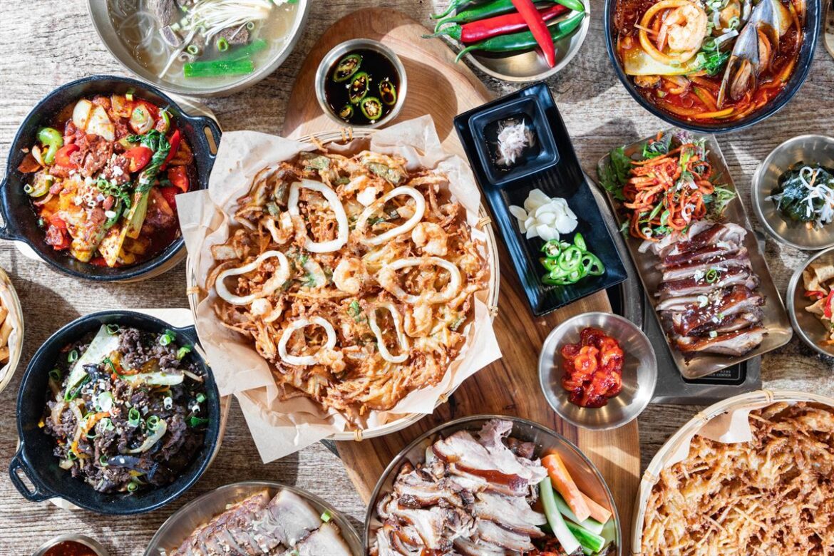 mixed Korean dishes including soup, noodles and banchan, Yi Dynasty Southport full table of Korean BBQ food at Yi Dynasty Southport Pick whichever matches the photo most closely — if it's mostly the grill and meat, go with the first or second; if it's more soups/sides/noodles together, the third fits better.