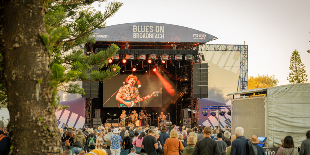 Diverse crowd enjoying live blues and roots music across multiple outdoor stages at a free music festival.