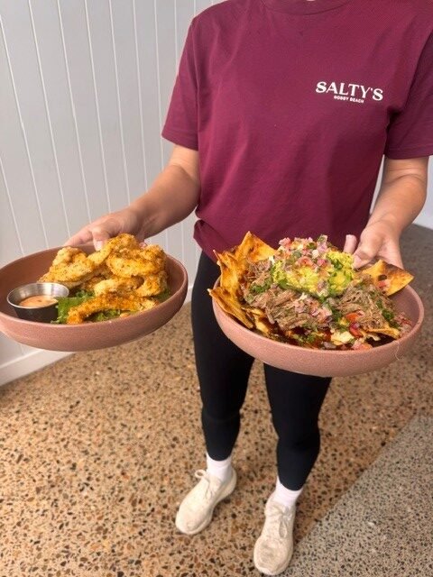Salt Nobby Beach staff member holding brisket nachos and native spiced calamari
